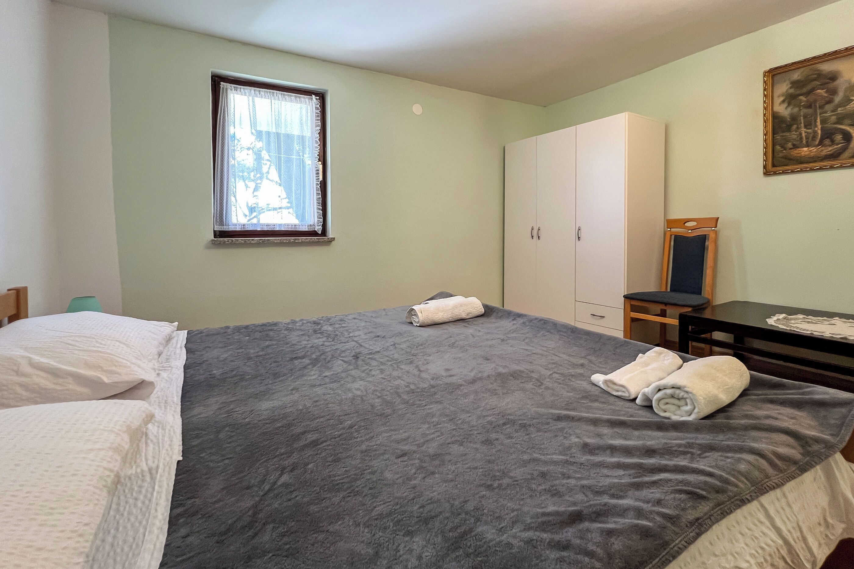 A bedroom with a bed, a wardrobe, a desk, and a window.