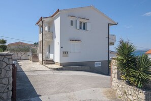 Ein zweistöckiges Gebäude mit einer Steinstufe, die zu einer Galerie führt, und Blick auf das Meer.