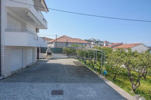 Eine Wohnstraße mit einem gepflasterten Weg, einem Metallzaun und Blick auf Häuser mit roten Ziegeldächern.