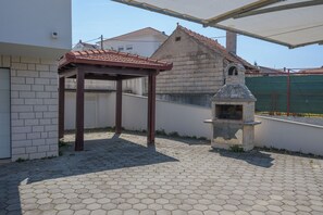 A patio area with a hexagonal tile floor, a pergola, and a stone-built barbecue grill. - Apartments Ivan (Okrug)