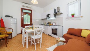 A compact kitchen with a dining area, a sofa, and a small table with a plant. - Apartment Vlatka Grof (Crikvenica)