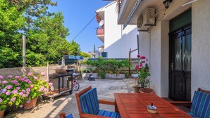 A patio with a wooden table and chairs, potted plants, and a bicycle. - Apartment Vlatka Grof (Crikvenica)