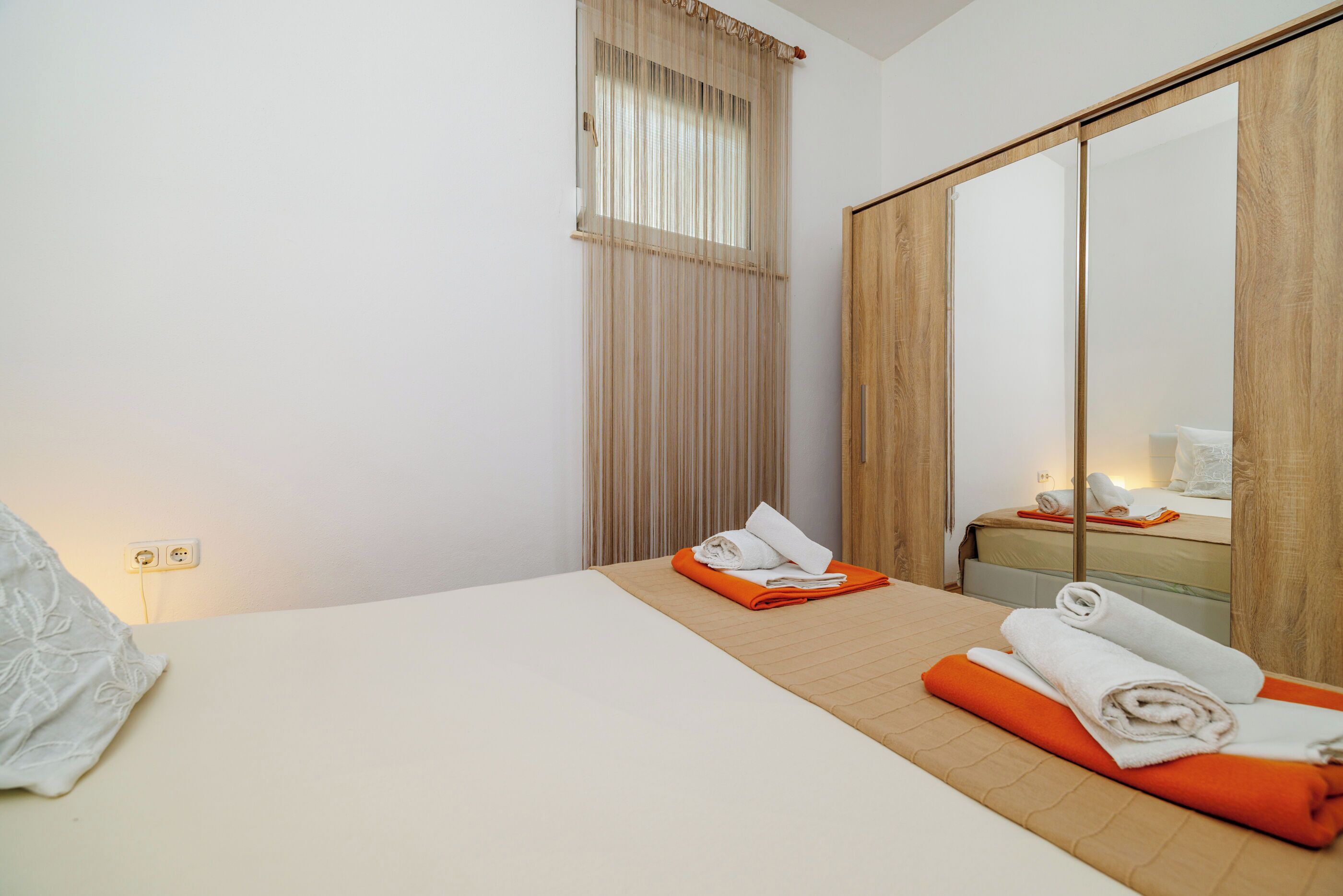 Ein Hotelzimmer mit einem Bett, einem Holzschrank, einem fenster mit Vorhängen und einem Nachttisch mit Lampe.