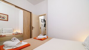 A hotel room with a bed, a bathroom mirror, a towel rack, and a framed picture on the wall. - Apartment Vlatka Grof (Crikvenica)