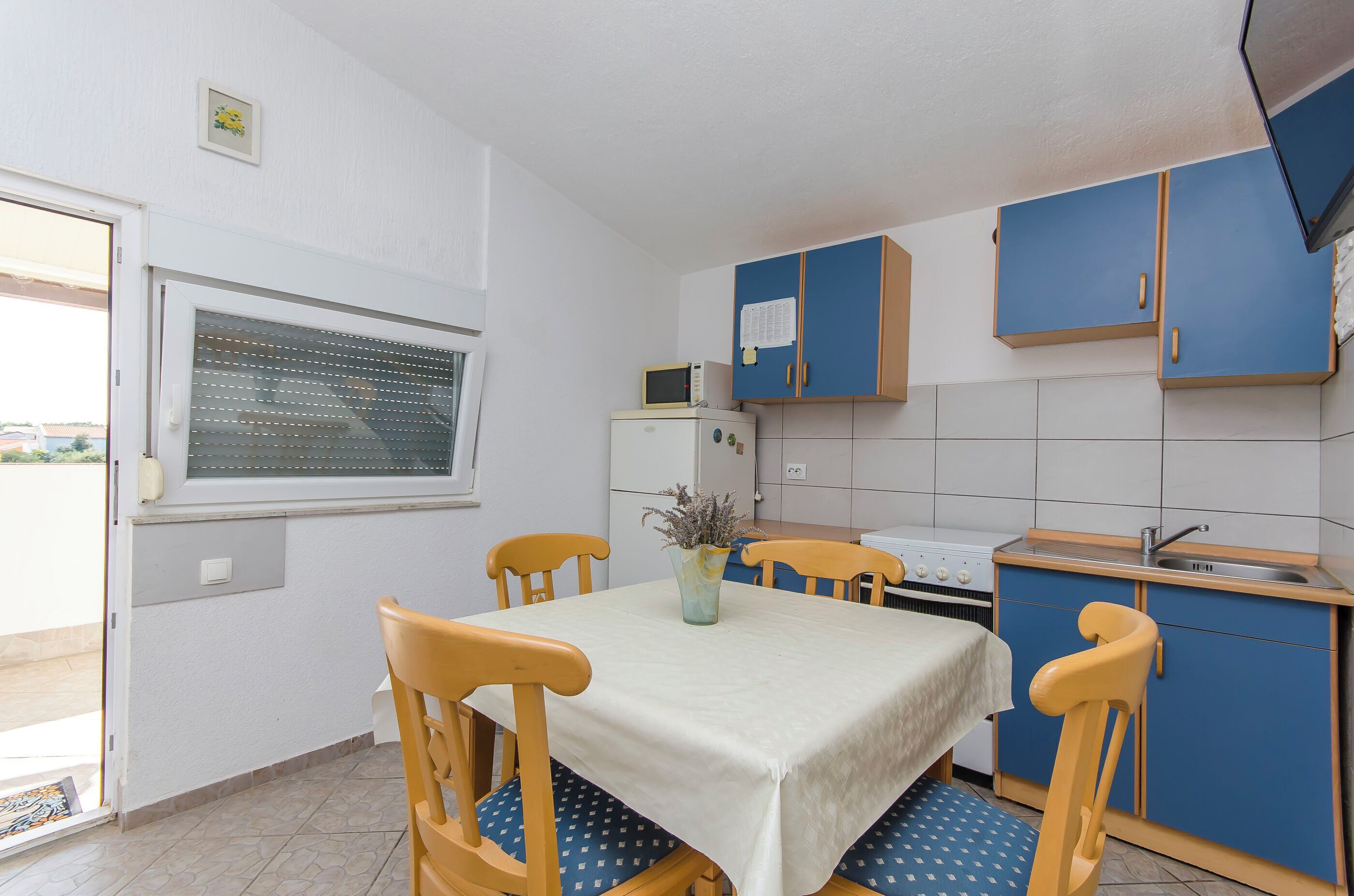 A small kitchen with a dining table, chairs, a microwave, and cabinets.