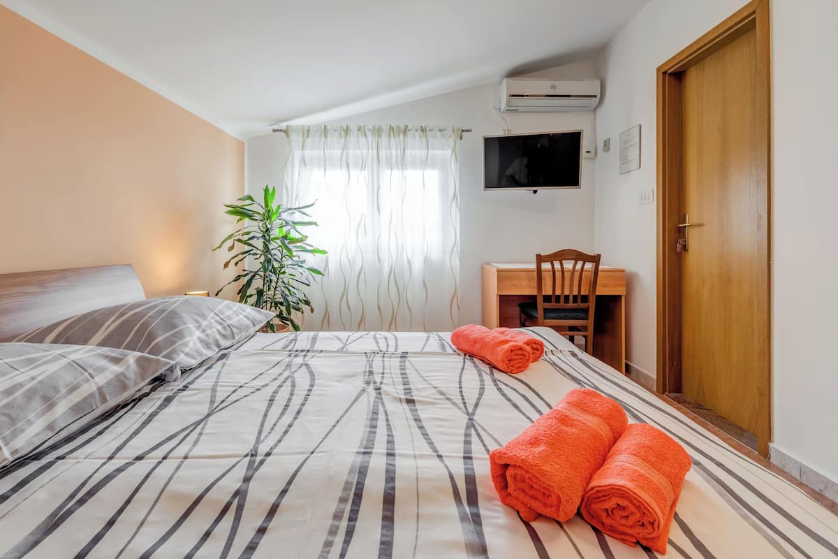 Hotellihuone, jossa on sänky, työpöytä, tuoli, televisio ja ovi.