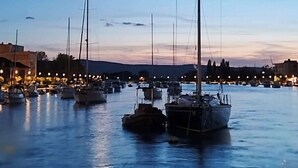A marina with several sailboats docked at night, under a clear sky with a visible moon. - Apartments Natalies Dream (Omis)