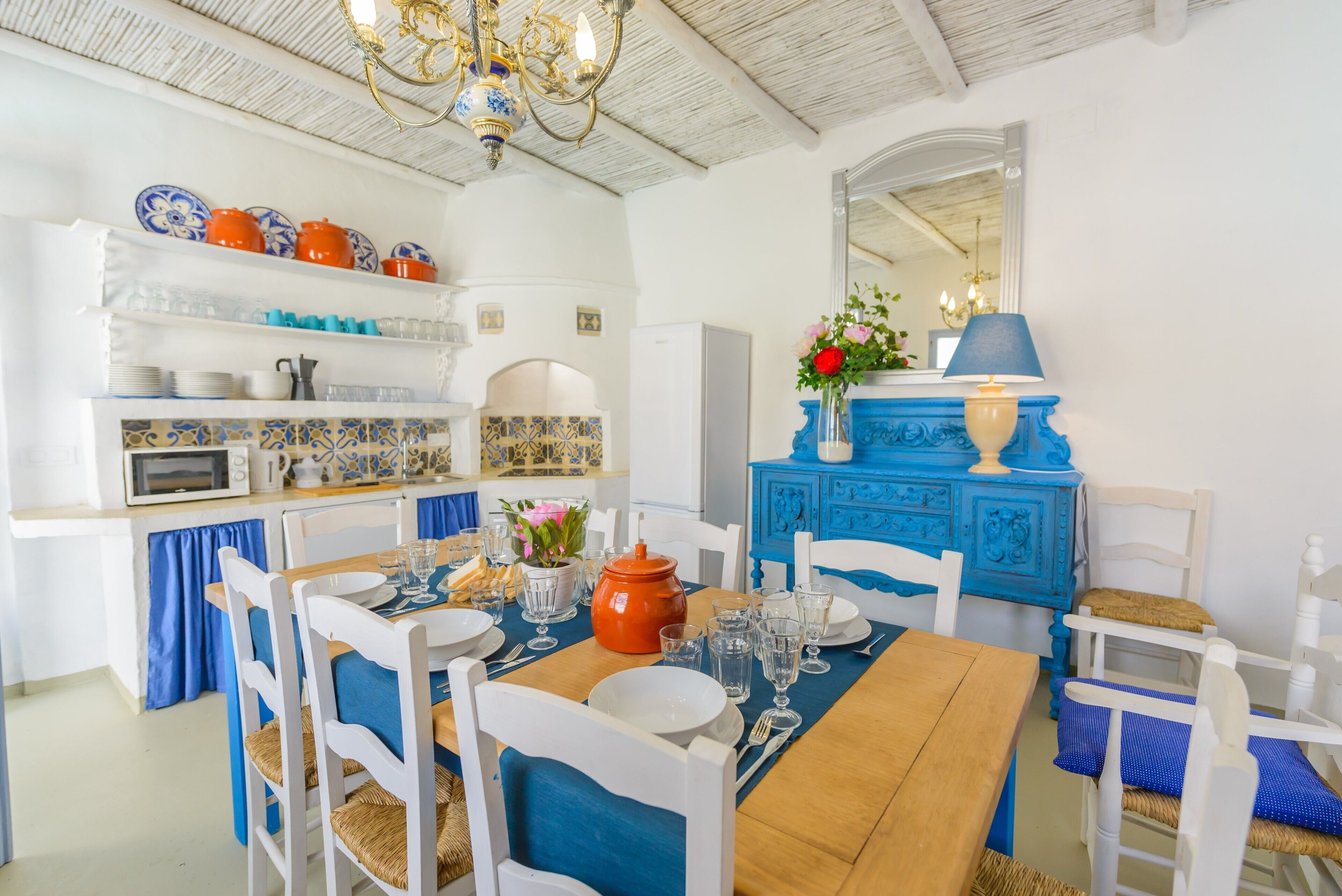 Un comedor con una mesa de madera, sillas blancas y una mesa decorada con camino de mesa azul.