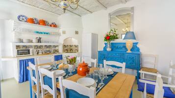 Un comedor con una mesa de madera, sillas blancas y una mesa decorada con camino de mesa azul.