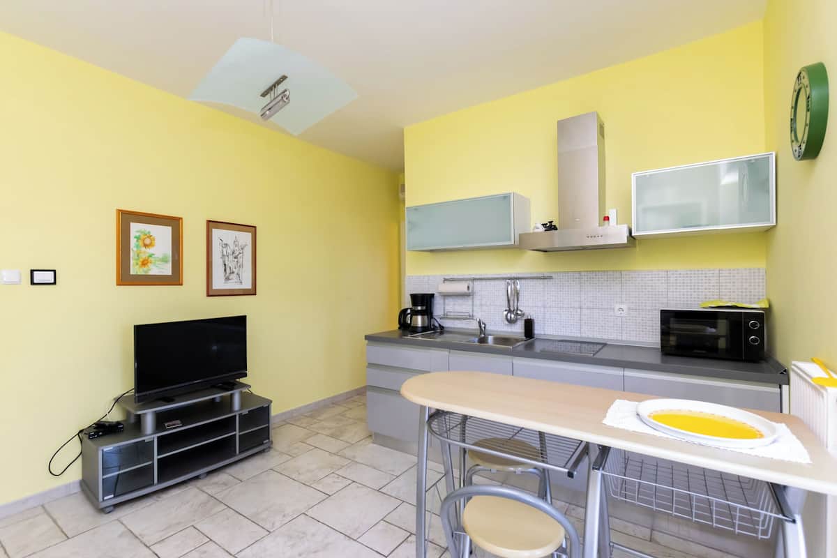 A compact kitchen with a TV, microwave, and a small dining area.
