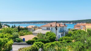 A coastal residential area with houses, a clear blue sky, and a view of the sea. - Apartments Rada i Stanislav (Rab)