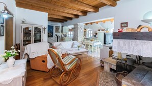Ein gemütliches Wohnzimmer mit Holzboden, einem Schaukelstuhl, einer Couch und einem Essbereich mit Tisch und Stühlen.