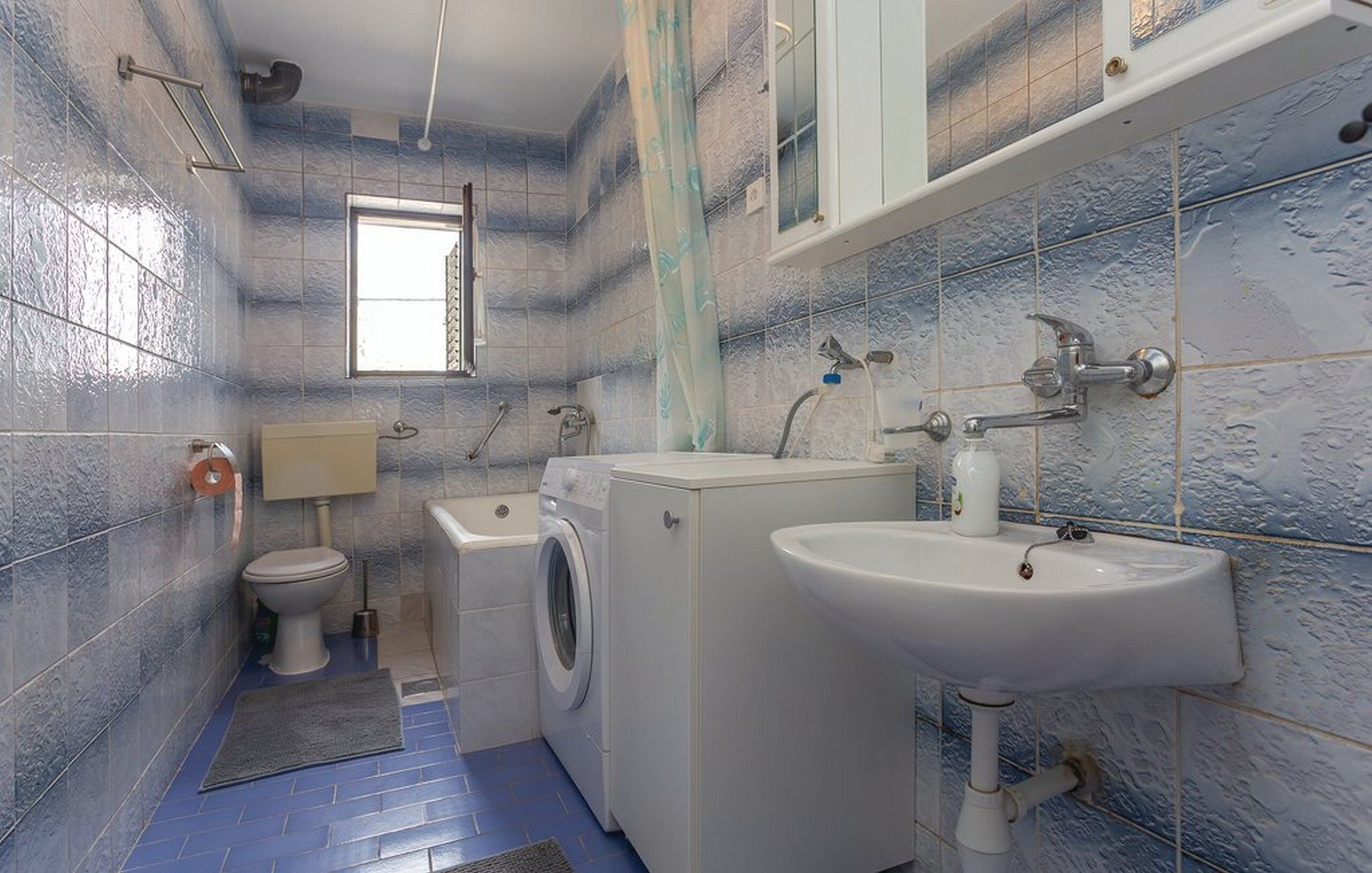 Un baño pequeño con inodoro, lavadora y lavamanos.
