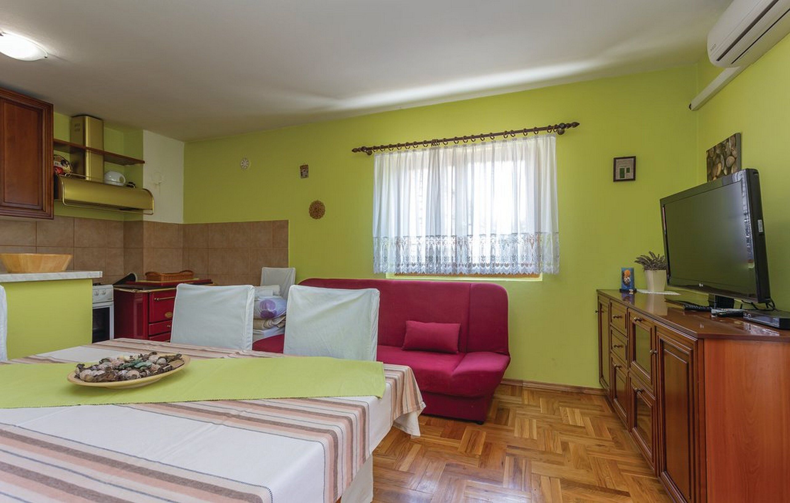 Ein kompakter Wohnbereich mit Küchenzeile, Essplatz, Sofa und Fernseher.