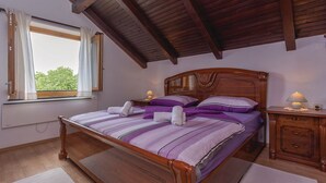 A bedroom with a wooden bed, a nightstand, a window with curtains, and a wooden ceiling. - House Rural Soul (Promina)