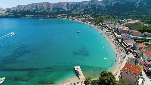 A coastal town with a beach, buildings, and mountains in the background. - House Kety (Baska)
