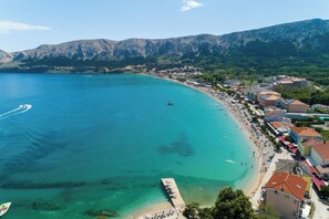 A coastal town with a beach, buildings, and mountains in the background. - House Kety (Baska)