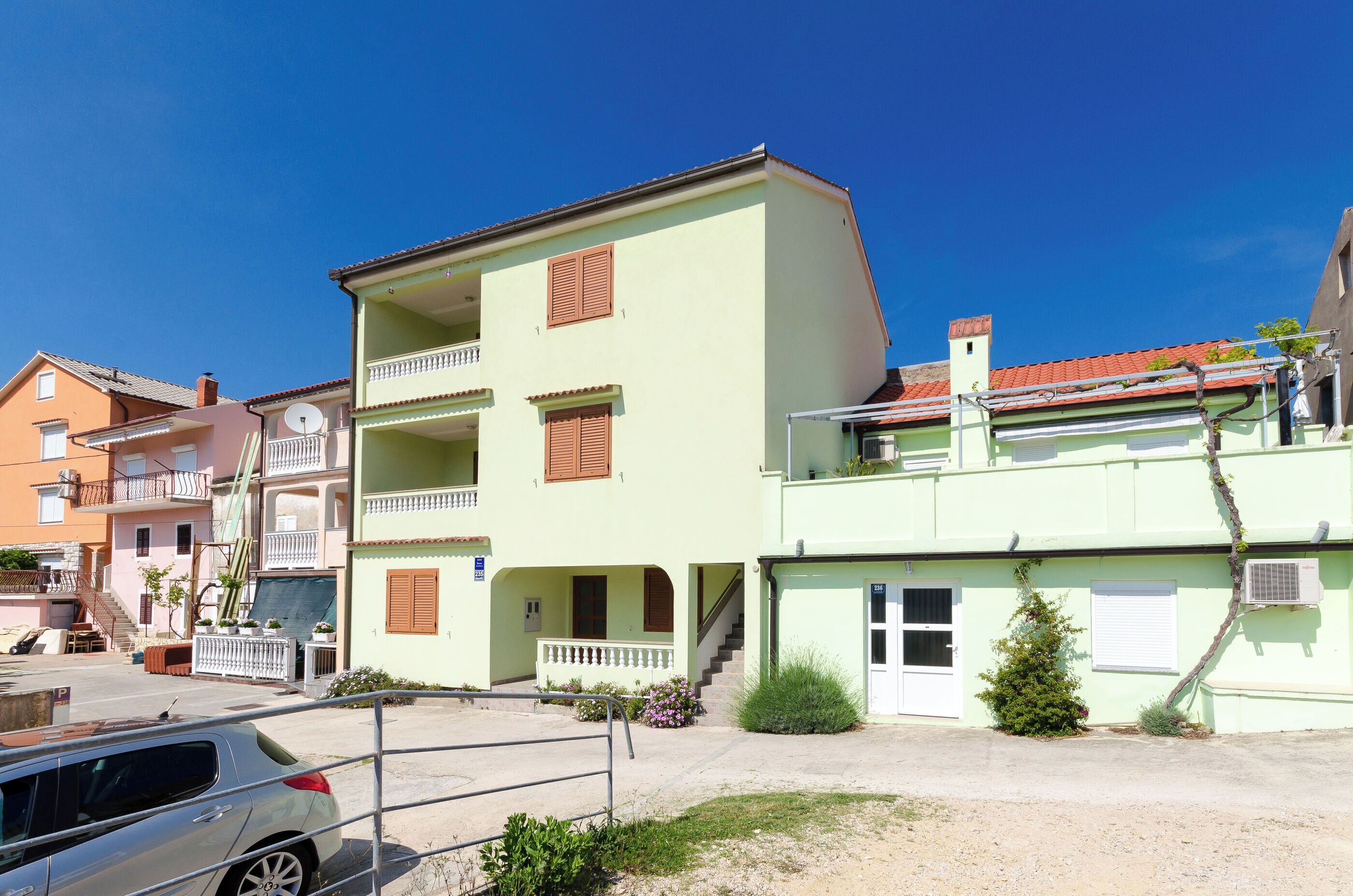 A multi-story building with balconies, a staircase, and a small garden area.