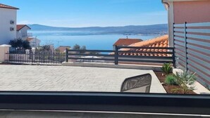A balcony with a view of a body of water and distant hills. - Apartments Valentina (Crikvenica)