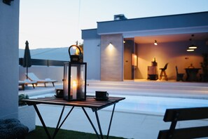 Un área de estar al aire libre moderna con una mesa, sillas y un farol.