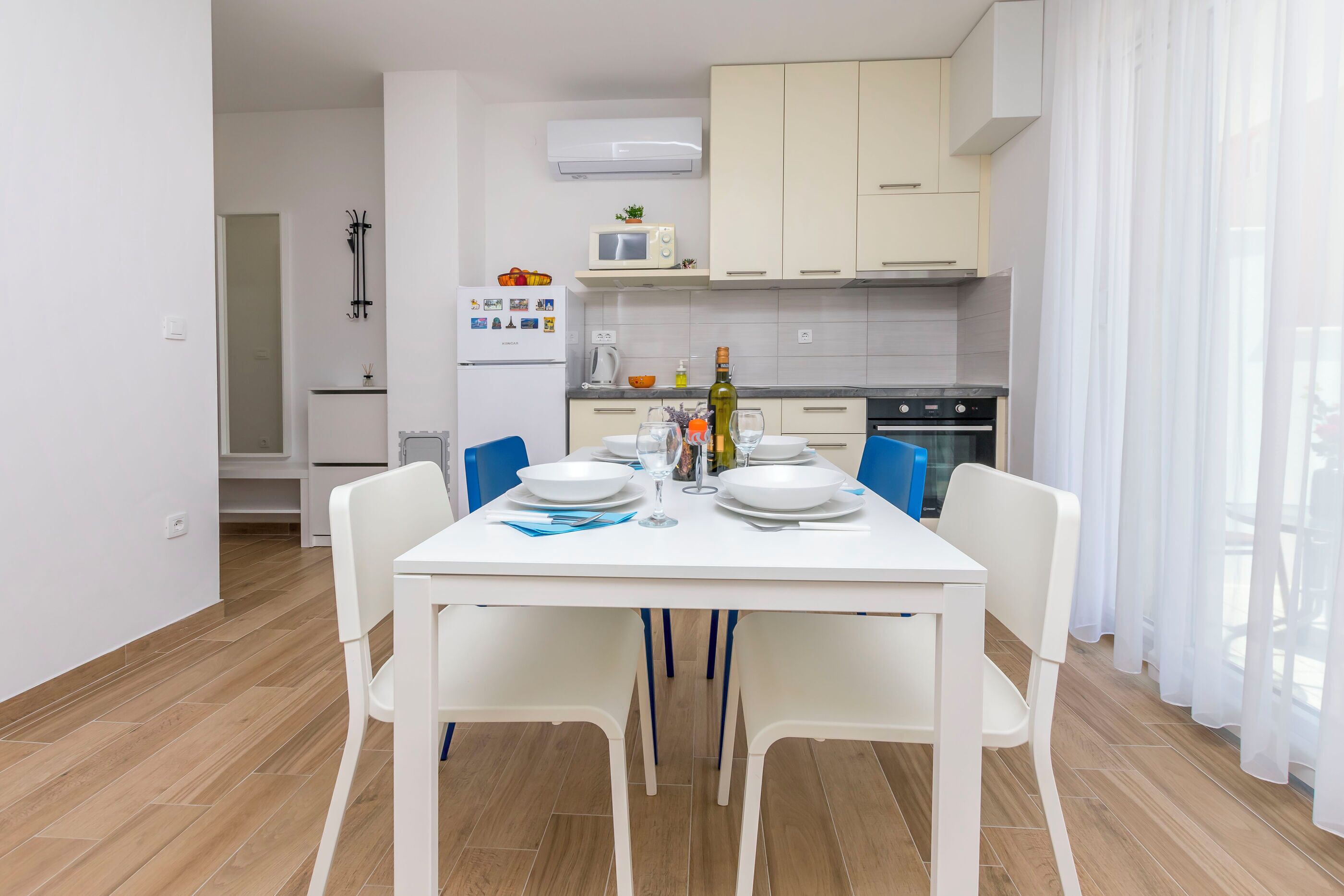 A modern kitchen with white cabinets, a microwave, and a dining table set for four.