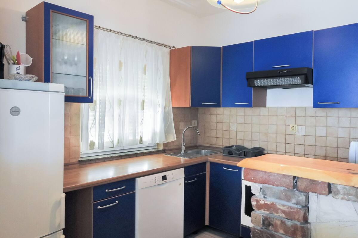 A compact kitchen with a refrigerator, dishwasher, and a stove.