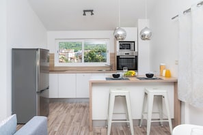 A modern kitchen with a large island, stainless steel appliances, and a view of a green landscape. - Apartments Ideal Holiday (Tribunj)