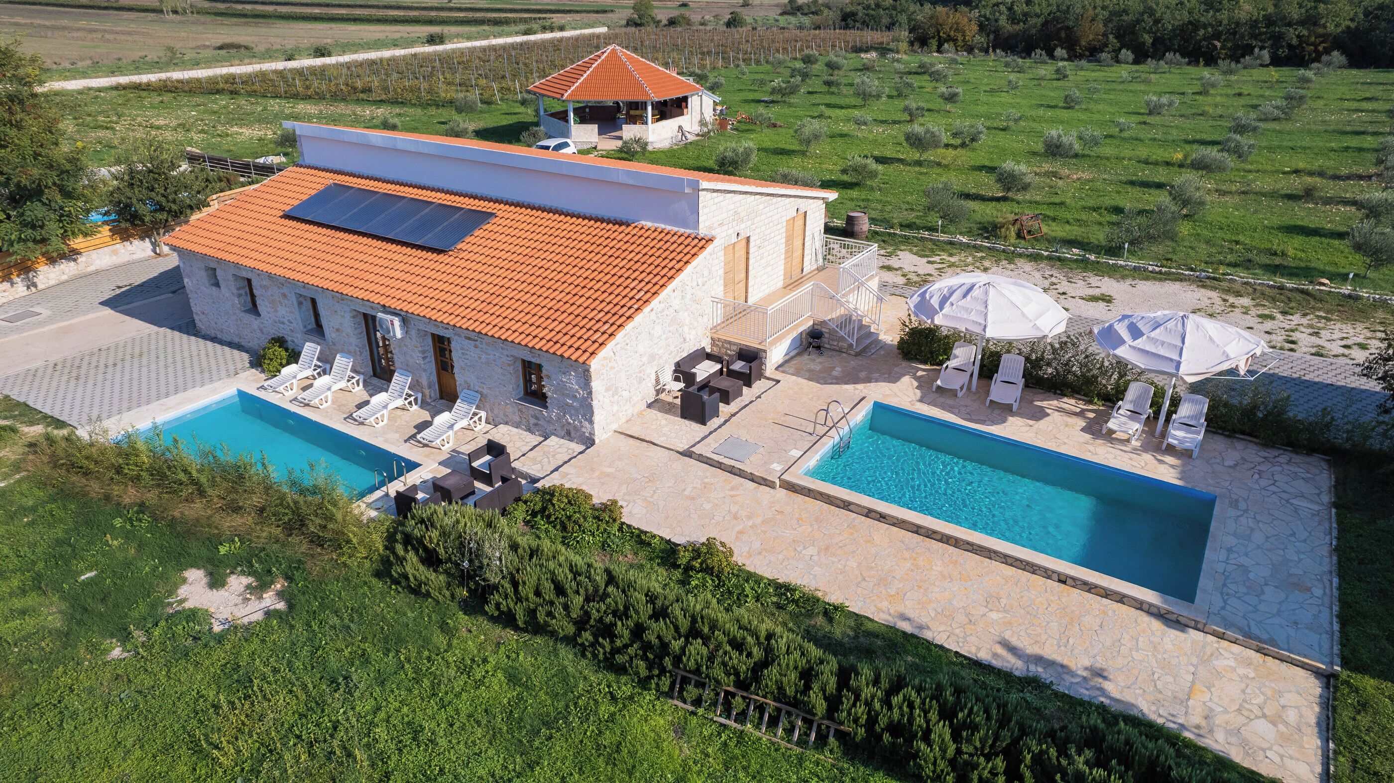 Una villa con piscina, mobiliario de exterior y jardín.
