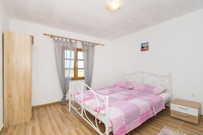 A bedroom with a bed, a nightstand, a wooden door, a window with curtains, and a small picture on the wall. - House Stone Curlew 4 (Benkovac)