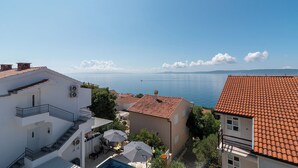 A coastal residential area with a clear view of the sea, a swimming pool, and terracotta-tiled buildings. - Apartment Vaya (Okrug)