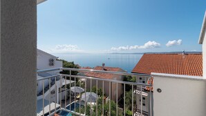 A balcony with a view of a swimming pool, a red-tiled roof, and a distant bridge. - Apartment Vaya (Okrug)