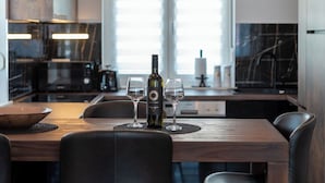 A modern kitchen with a central island, two pendant lights, and a wine bottle. - Apartment Vaya (Okrug)