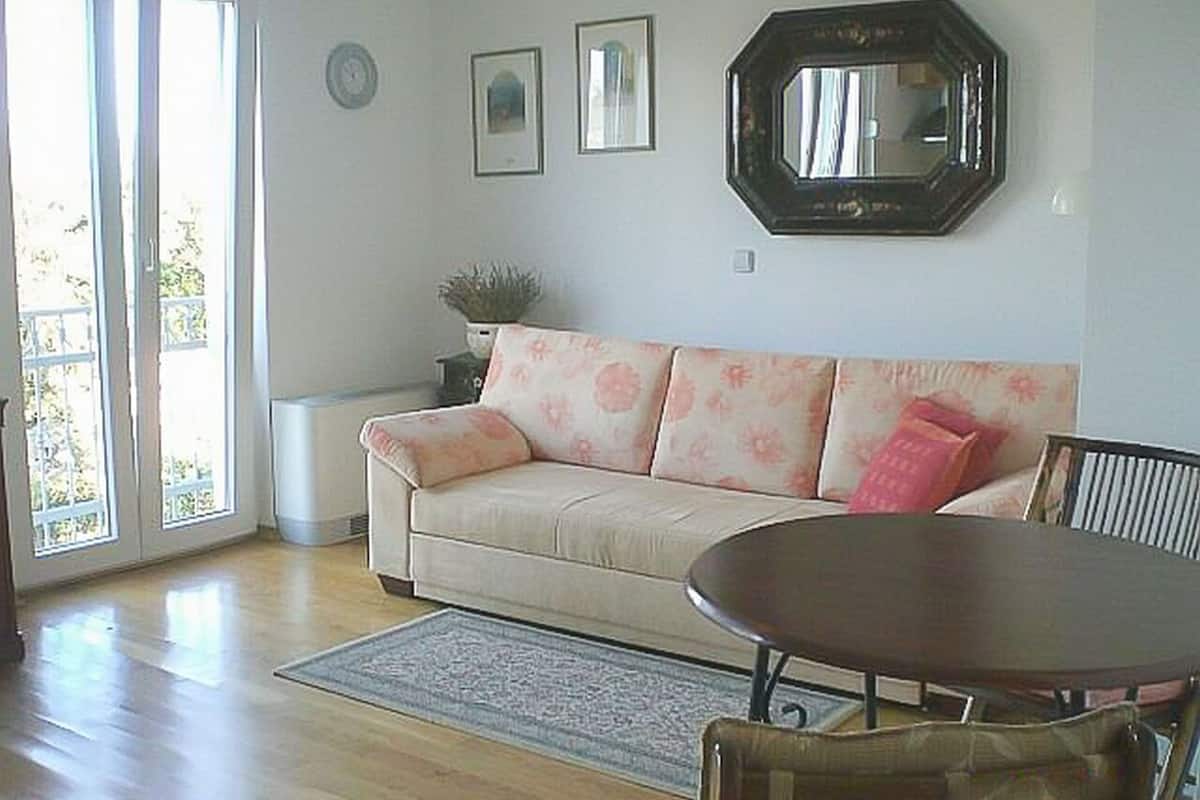 A living room with a beige sofa, a round table, and a large mirror on the wall.
