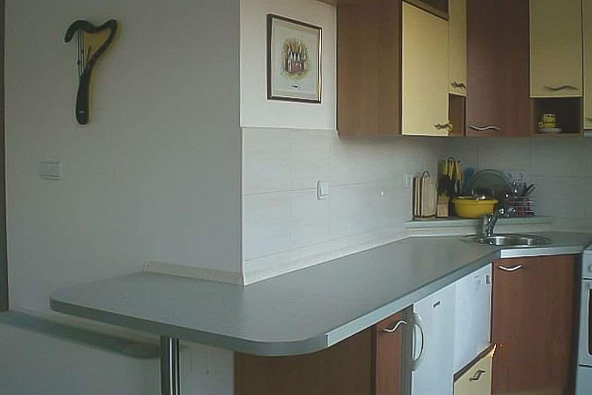 A kitchen with white cabinets, a sink, and a small countertop.