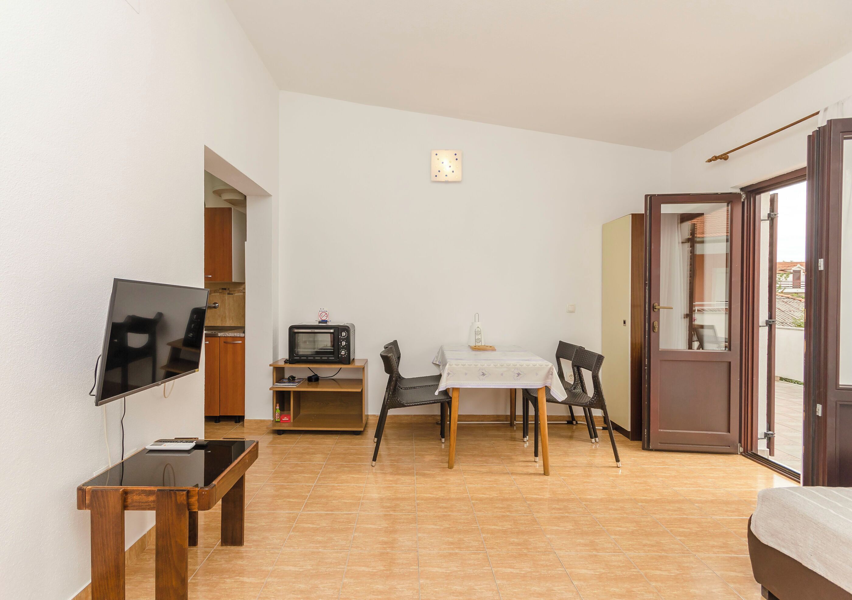 A compact living space with a TV, a dining table, and a kitchenette.