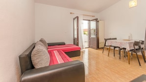Et værelse med en sofa, et spisebord med stole og en skydedør til et udendørs område.