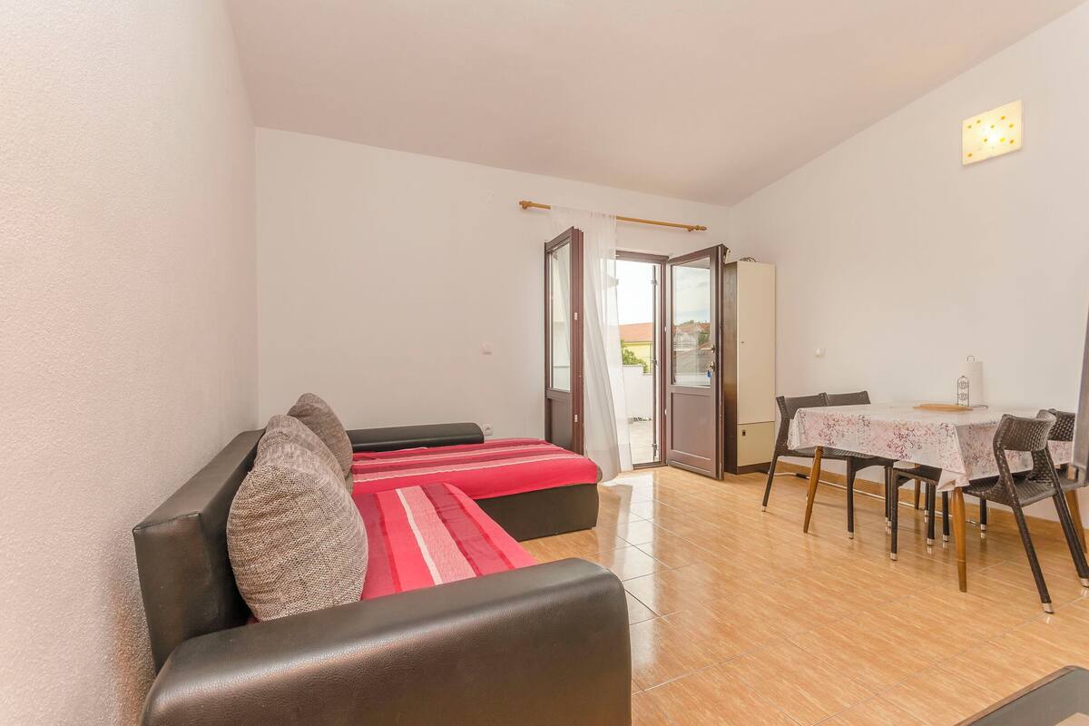 Une pièce comprenant un canapé, une table à manger avec des chaises et une porte-fenêtre coulissante donnant sur un espace extérieur.