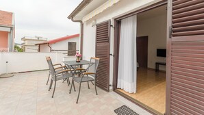 En balkon med et bord og stole, en skydedør og udsigt til indretningen.