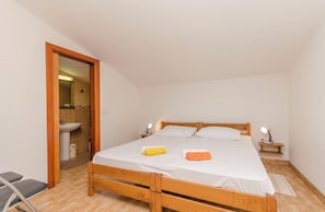 A single-bed room with a wooden frame, white bedding, two bedside lamps, and a small bedside table. - Apartments Rusan (Vodice)