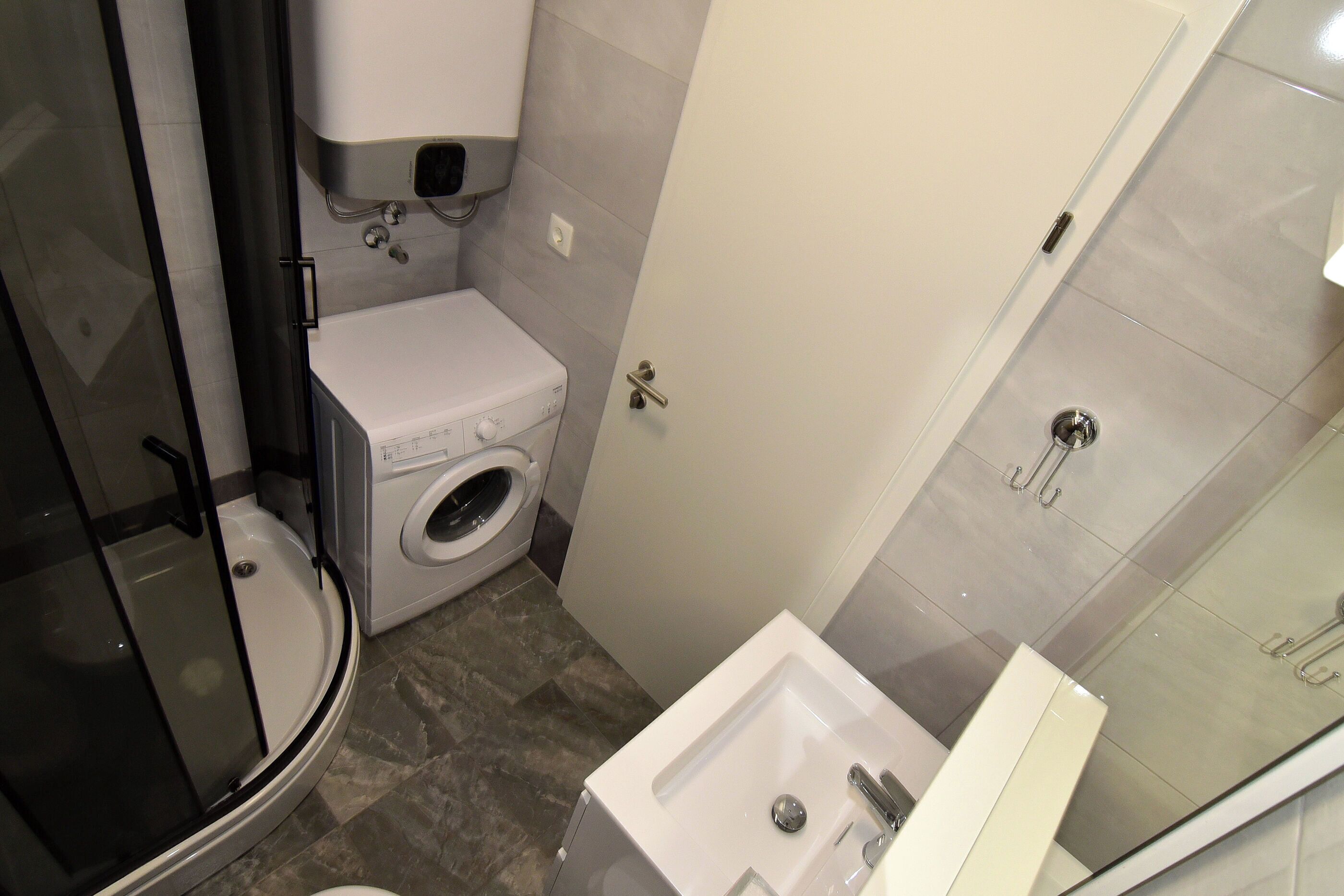 Ein kleines Badezimmer mit Toilette, Waschmaschine und einer Duschkabine.