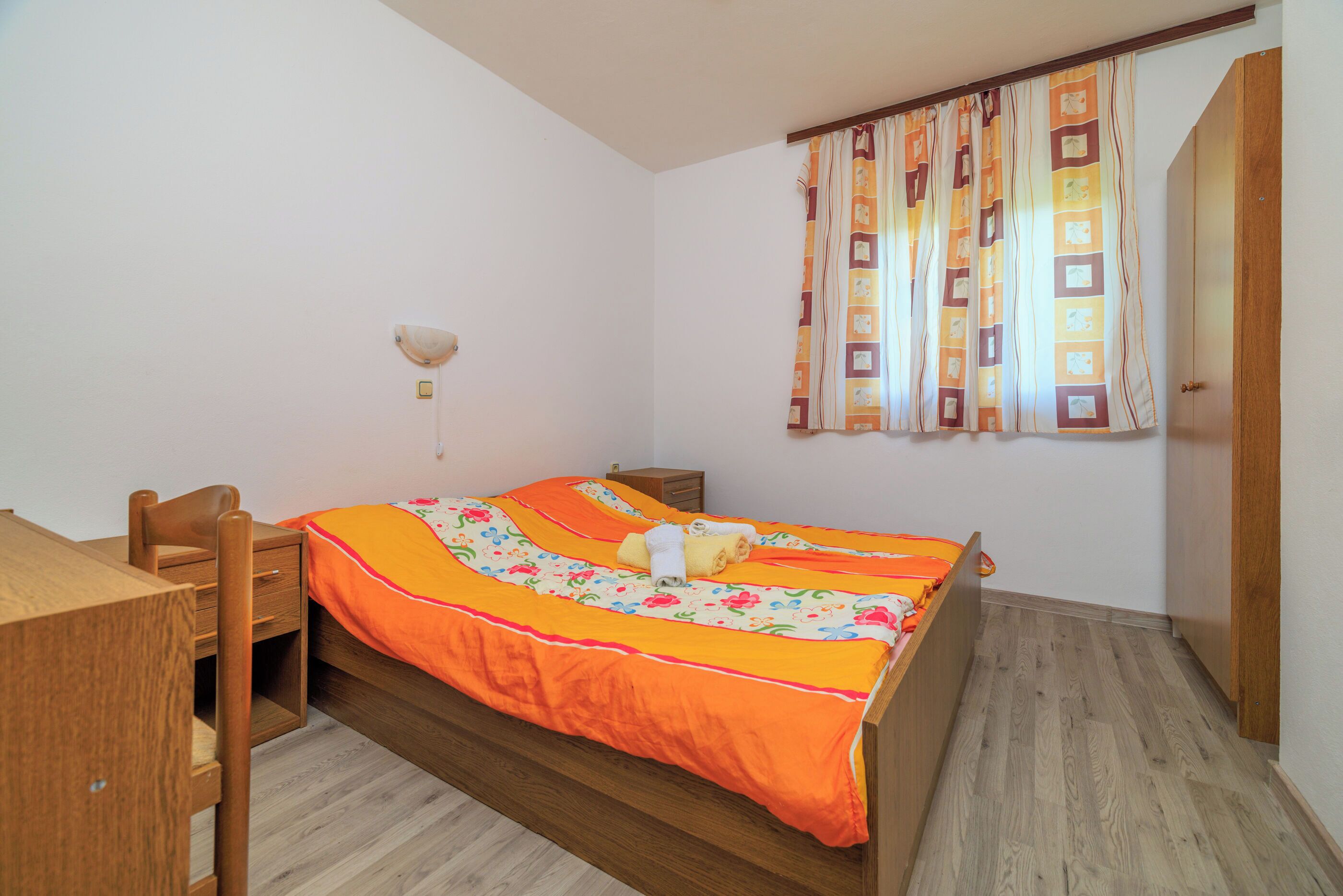 A bedroom with a wooden bed, a desk, and a nightstand.