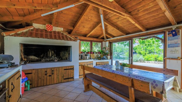 Une cuisine rustique avec des poutres en bois, un grand banc en bois et un sol carrelé.