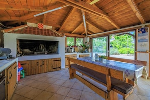 A rustic kitchen with wooden beams, a large wooden bench, and a tiled floor. - Apartments Milorad M (Lopar)