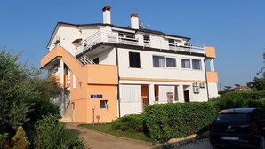 Una casa a due piani con un balcone, una scala e un'auto parcheggiata davanti.