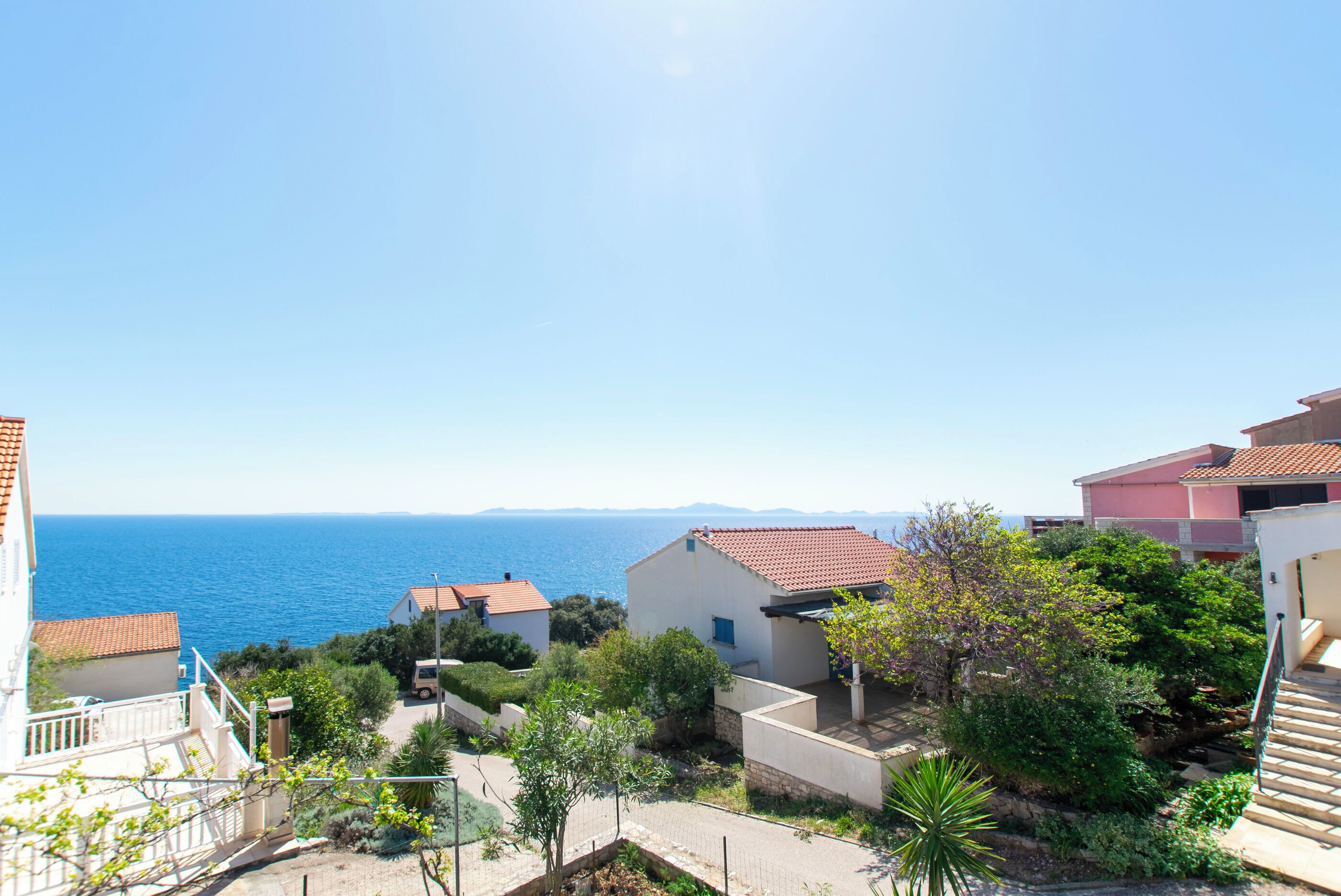 Zona residencial costera con casas, cielo despejado y el mar al fondo.