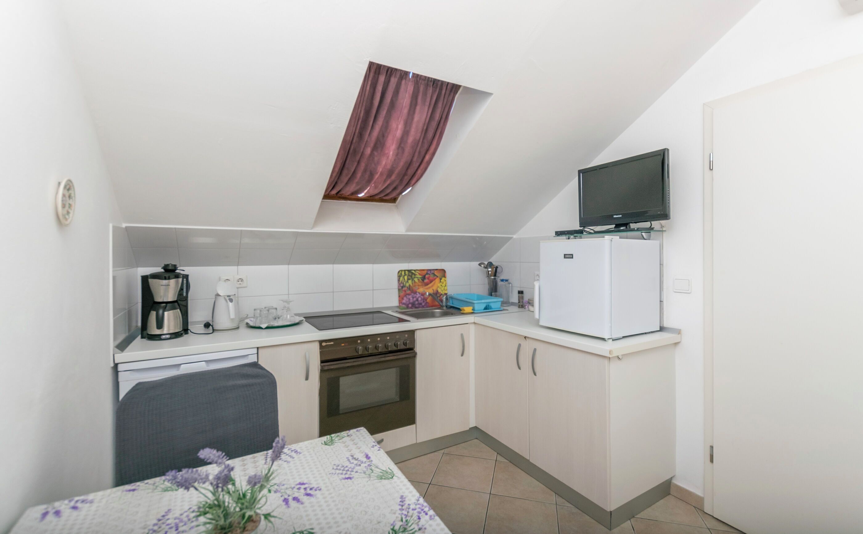 Cocina compacta con estufa, horno, cafetera y refrigerador pequeño.
