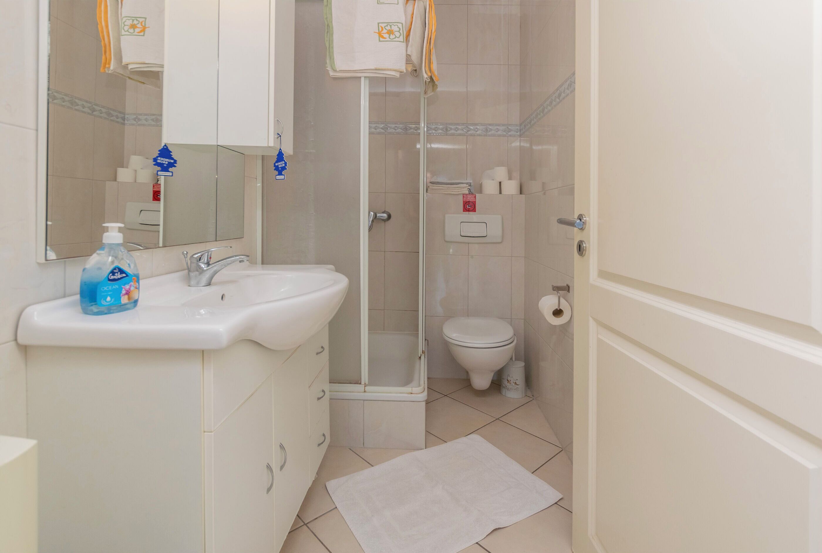 A bathroom with a sink, mirror, toilet, and shower.