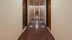 A long, narrow hallway with wooden doors on either side and a shiny tiled floor. - The Sangam Hotel Mahabaleshwar (Mahabaleshwar)