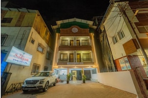 A two-story building with a sign reading "The Sangan" and a parked SUV in front.