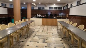 A conference room with a long table, chairs, and a counter with staff. - The Sangam Hotel Mahabaleshwar (Mahabaleshwar)